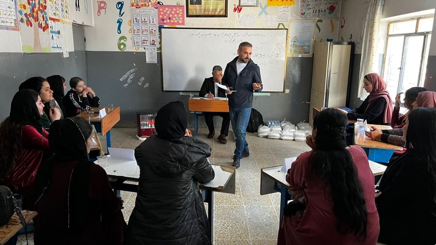 A DCD trainer leading a community training session in a classroom