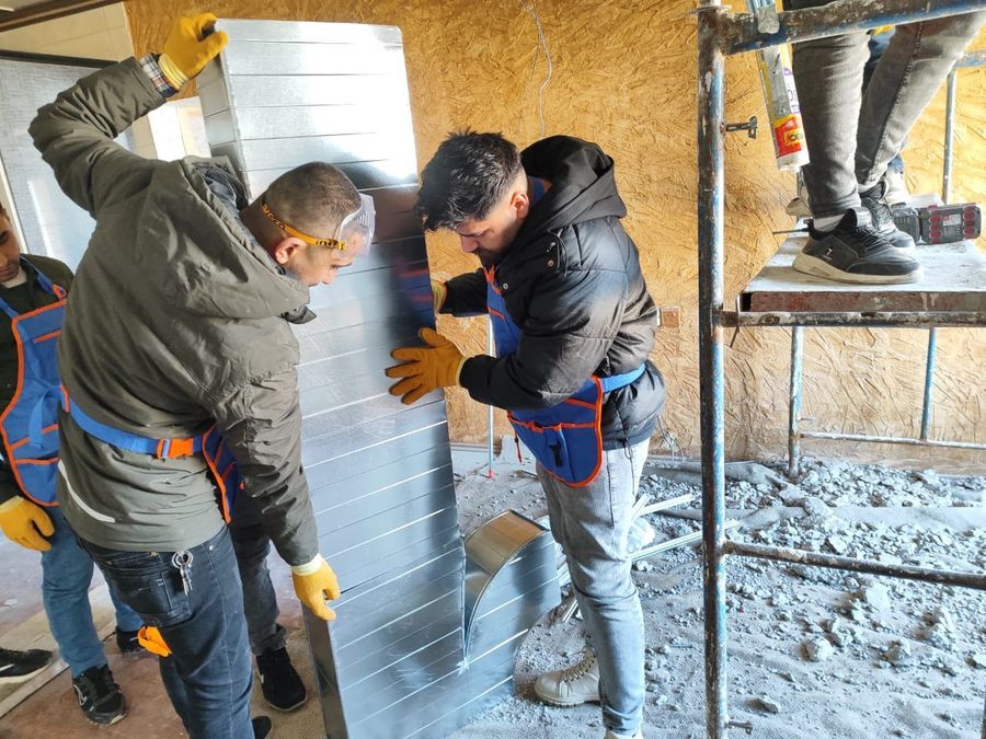 Trainees installing insulated ducting on site during vocational training